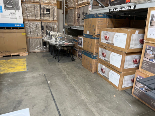 Workers packing heavy-duty cartons with protective wrapping materials in a bright factory setting.