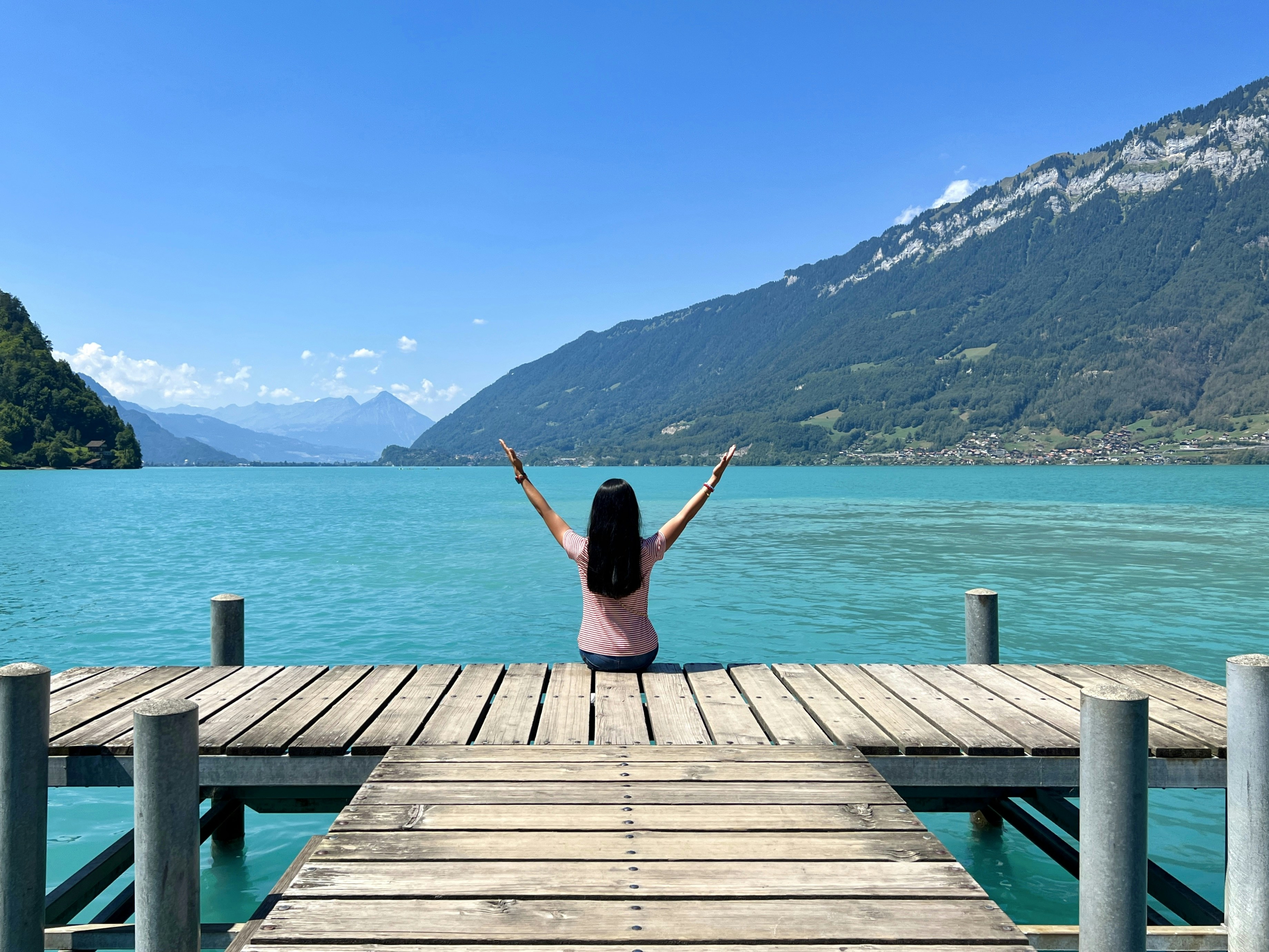 a woman sitting on a dock with her arms outstretched