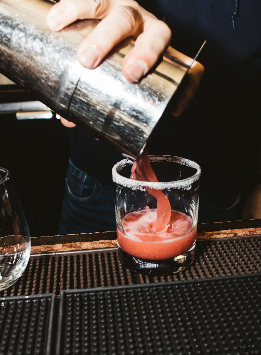 a person pouring a drink into a glass