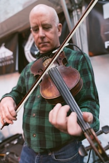A close-up shot of Stewart passionately playing his fiddle with vibrant green music notes floating around him.