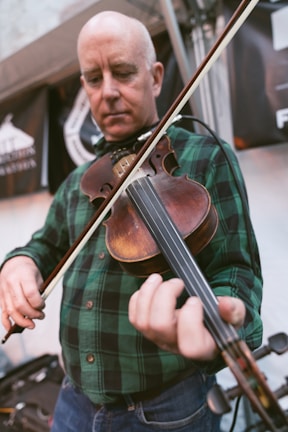 Stewart passionately playing his fiddle on a sunlit stage with green Irish decorations.