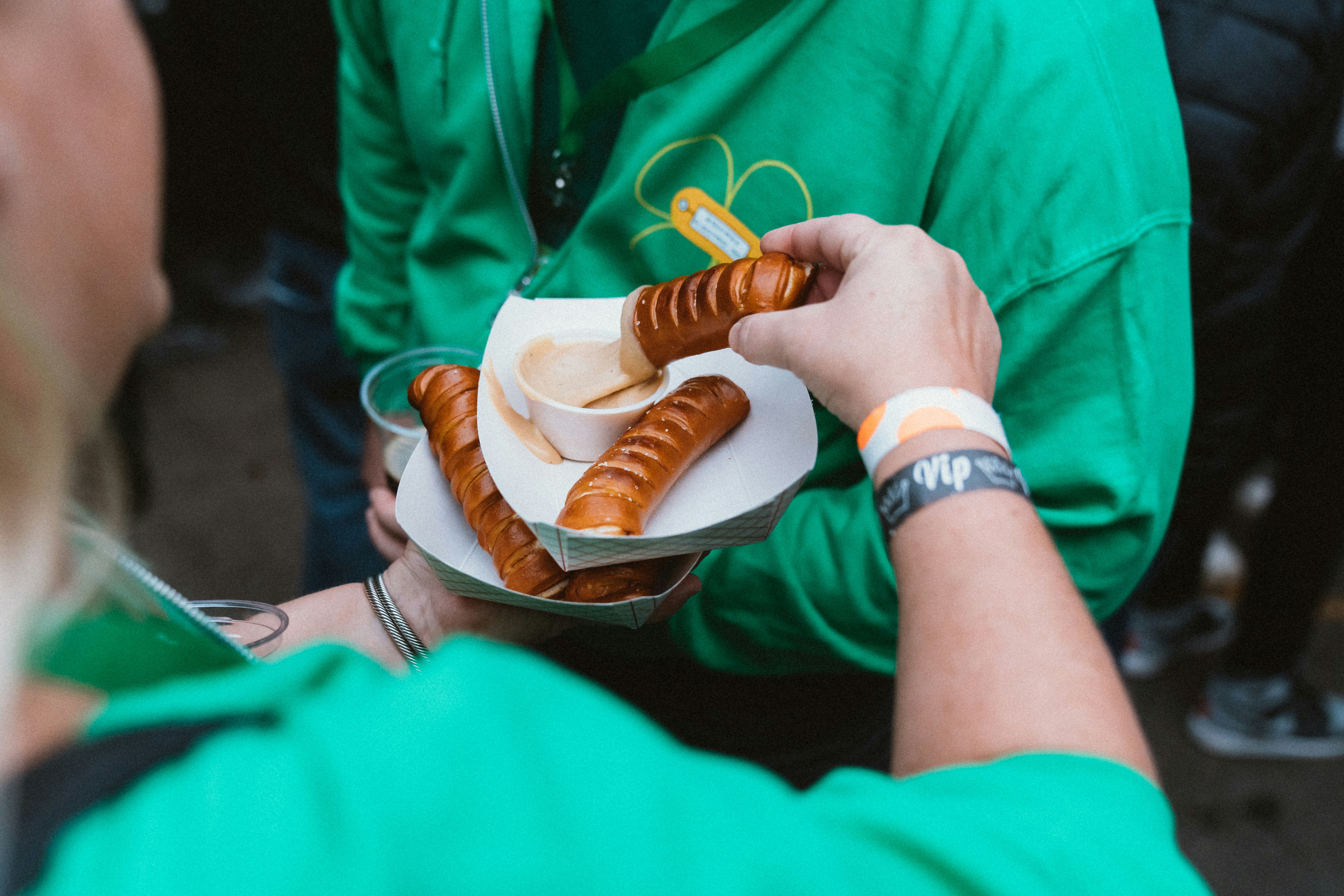 a woman in a green shirt holding a plate of hot dogs