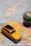 A small, vintage yellow toy car is placed on a map of Europe, highlighting cities in countries like Italy, France, and Switzerland. A small globe is partially visible on the right, emphasizing travel and exploration themes.