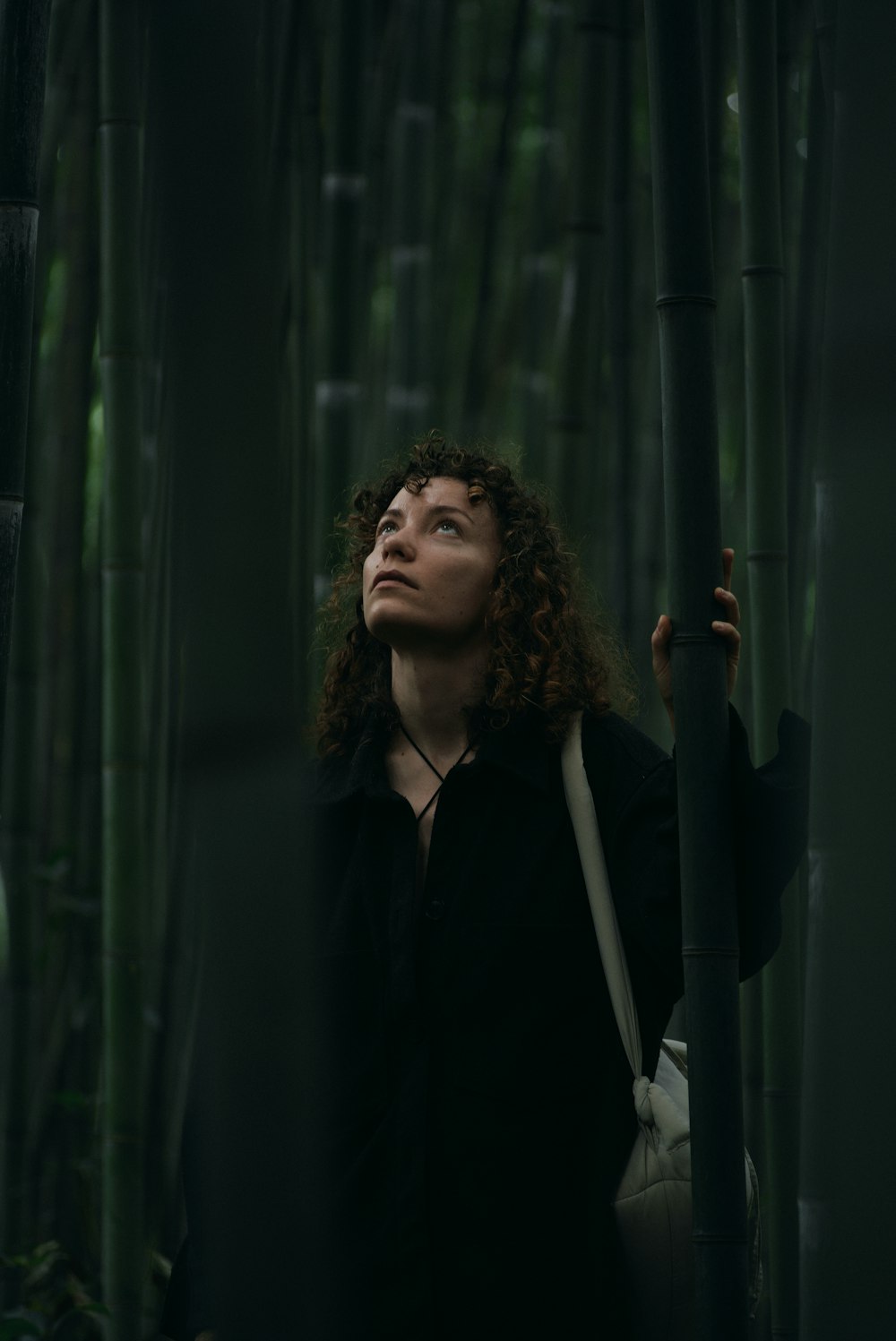 a woman standing in front of a bamboo tree