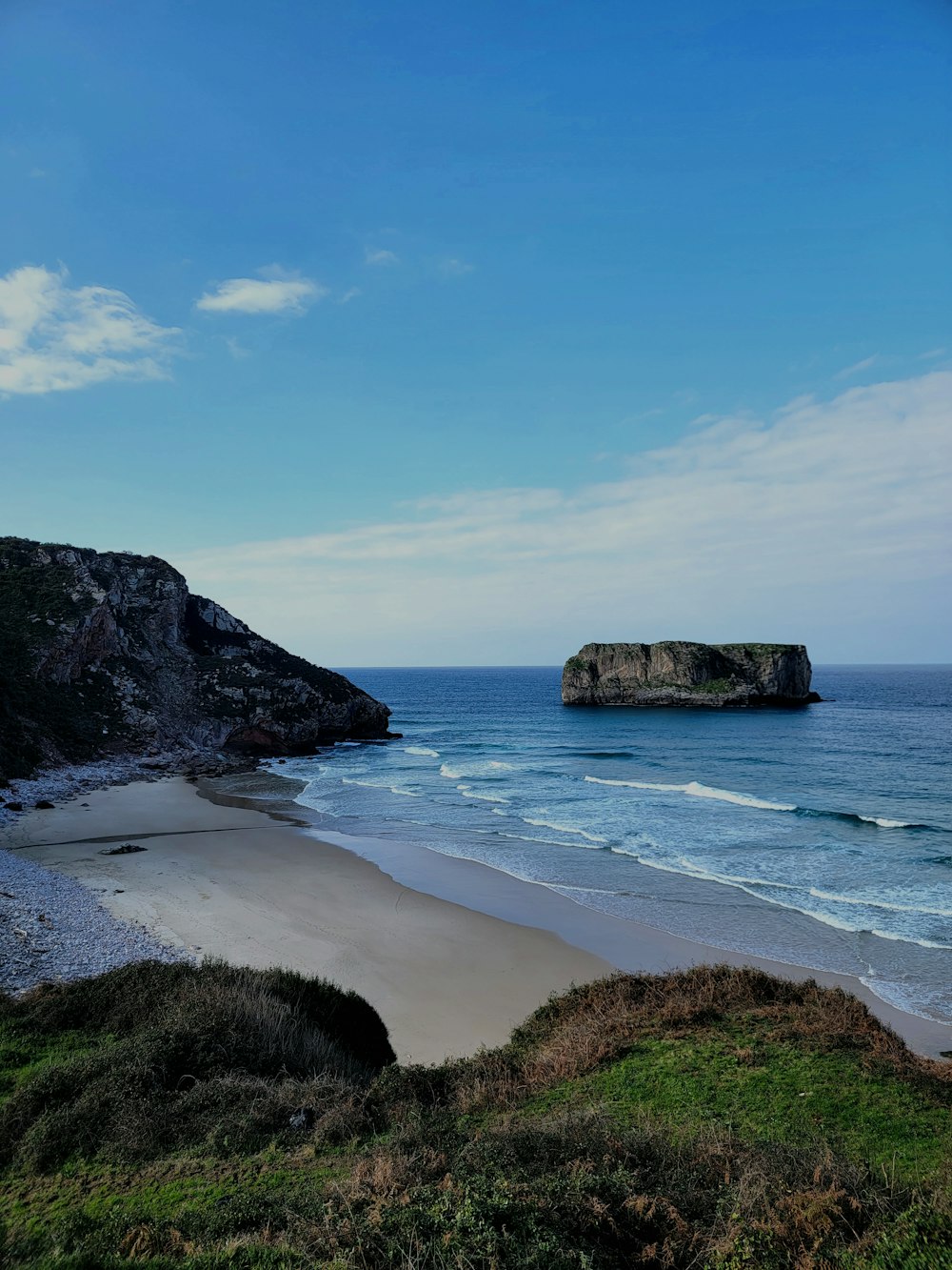 a beach with a rock outcropping in the distance