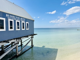 a blue building sitting on top of a beach next to the ocean
