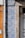 Detailed blue and white patterned tiles are adorning a wall, featuring intricate designs next to a section of exposed beige stone. A vertical metal pipe runs along the left side of the wall. Adjacent sections of the wall feature orange tiles, creating a contrast with the patterned tiles.