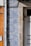 Detailed blue and white patterned tiles are adorning a wall, featuring intricate designs next to a section of exposed beige stone. A vertical metal pipe runs along the left side of the wall. Adjacent sections of the wall feature orange tiles, creating a contrast with the patterned tiles.