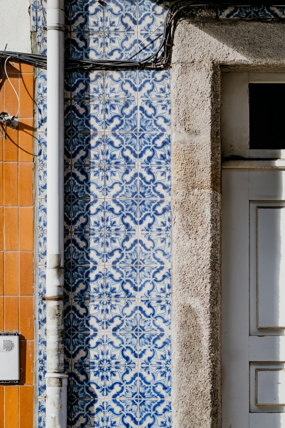 a blue and white tiled wall next to a white door