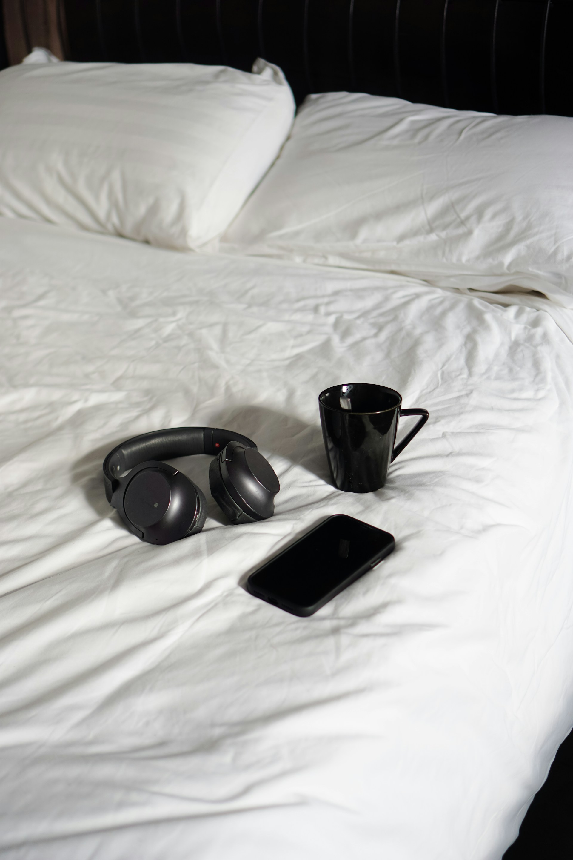 a pair of headphones and a phone on a bed