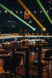 Outdoor riverside dining area with wooden tables and soft ambient lighting at sunset.