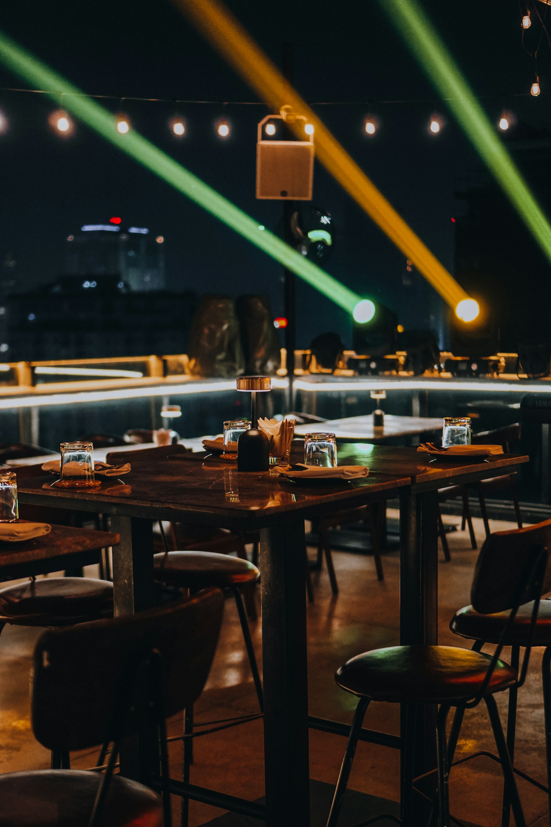 The spacious outdoor terrace set for a group dinner with rustic wooden tables and soft ambient lighting.