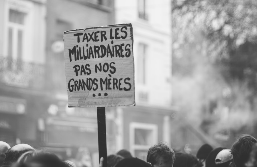 a protest sign in front of a crowd of people