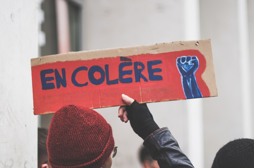 a person holding a sign that says en colere