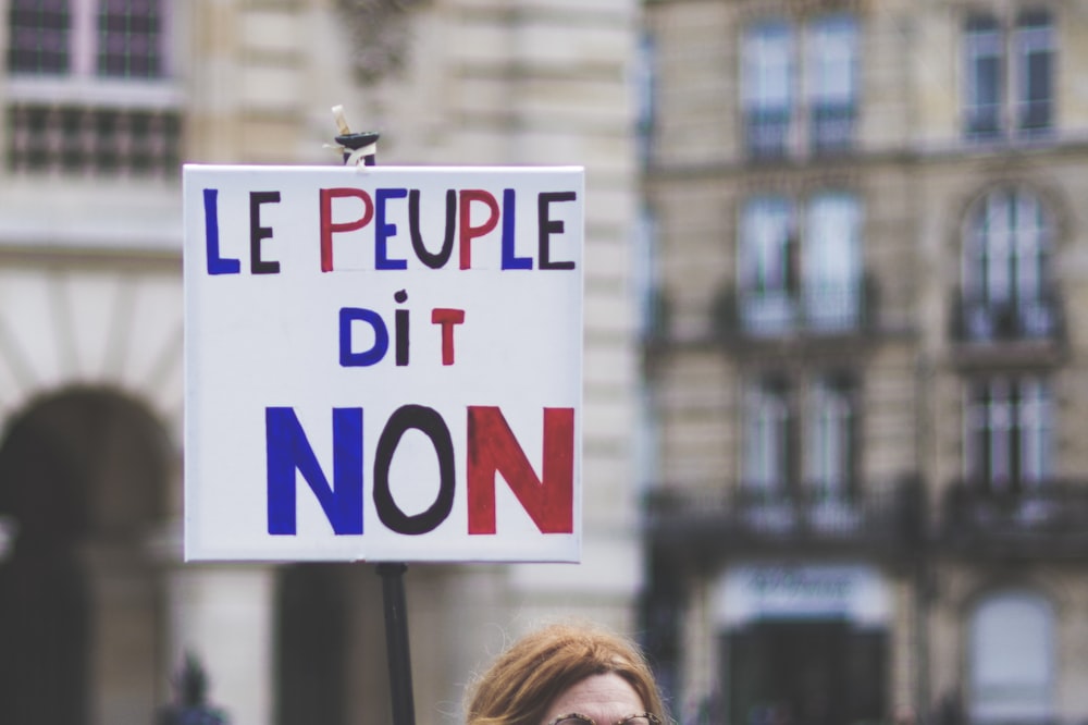a woman holding a sign that says le peuple dit non