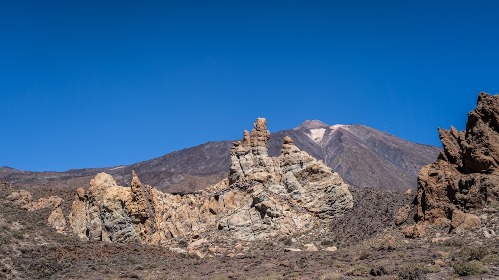 a group of rocks in the desert with a mountain in the background