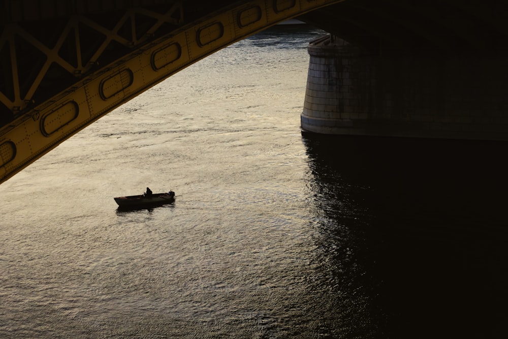 a person in a small boat under a bridge