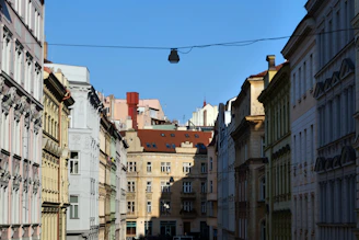 A scenic view of a historic European city street lined with colorful buildings under a bright sky.