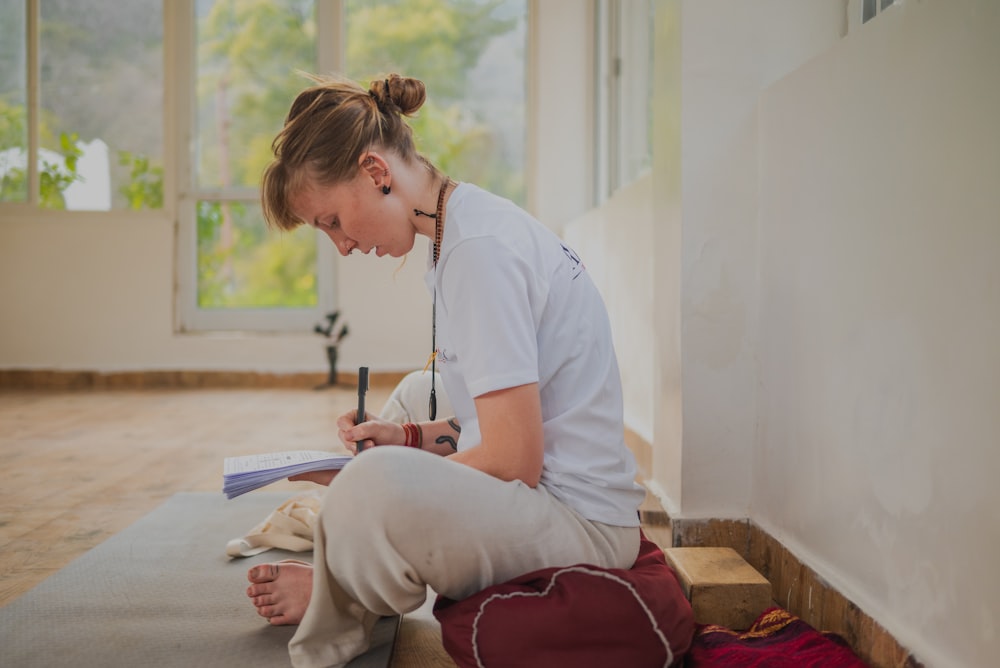 a woman sitting on the floor looking at a book