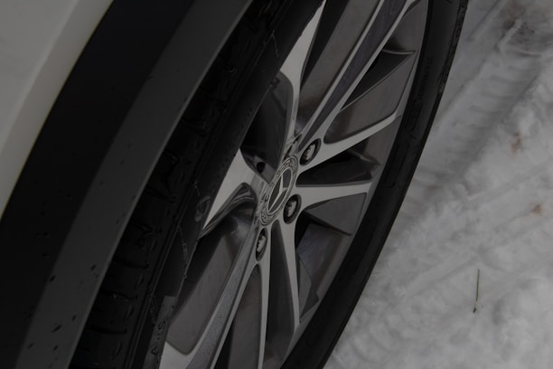 Close-up of winter tires stacked neatly next to a car in the workshop.