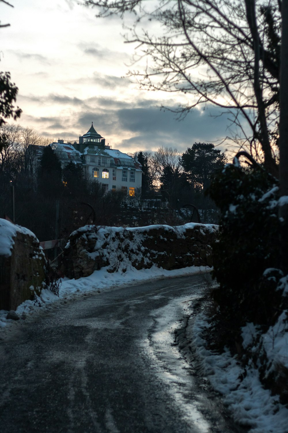 a road with snow on the ground and a building in the background