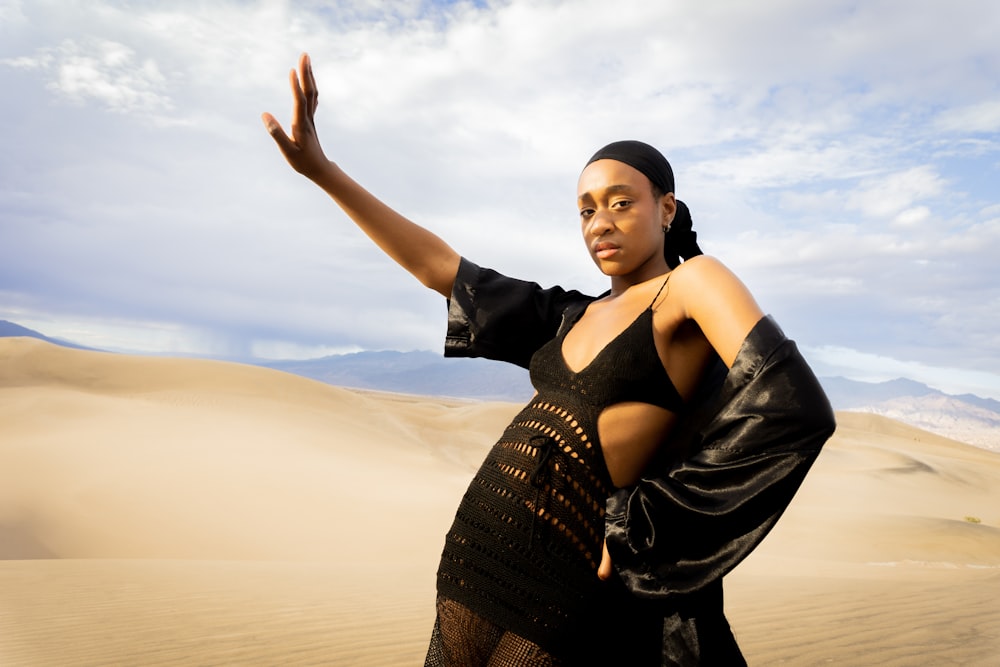 uma mulher em um vestido preto de pé no deserto