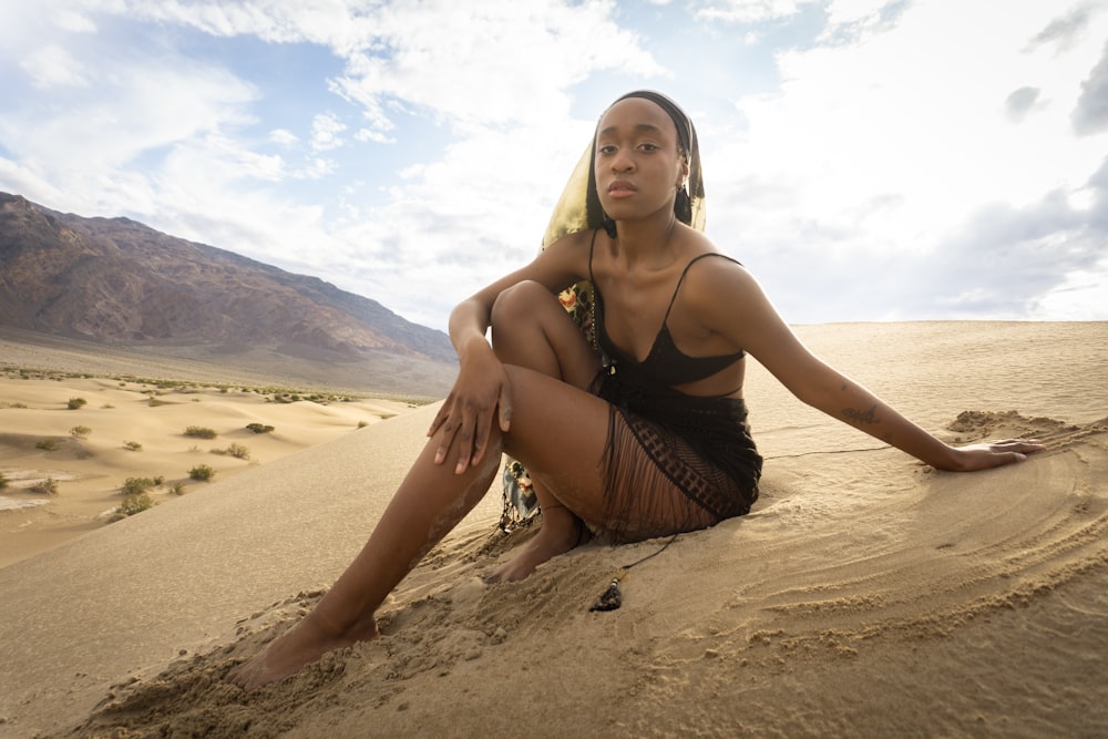 uma mulher sentada no topo de uma duna arenosa