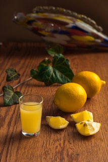A vibrant glass of fresh lemon juice with vitamin C tablets on a rustic wooden table.