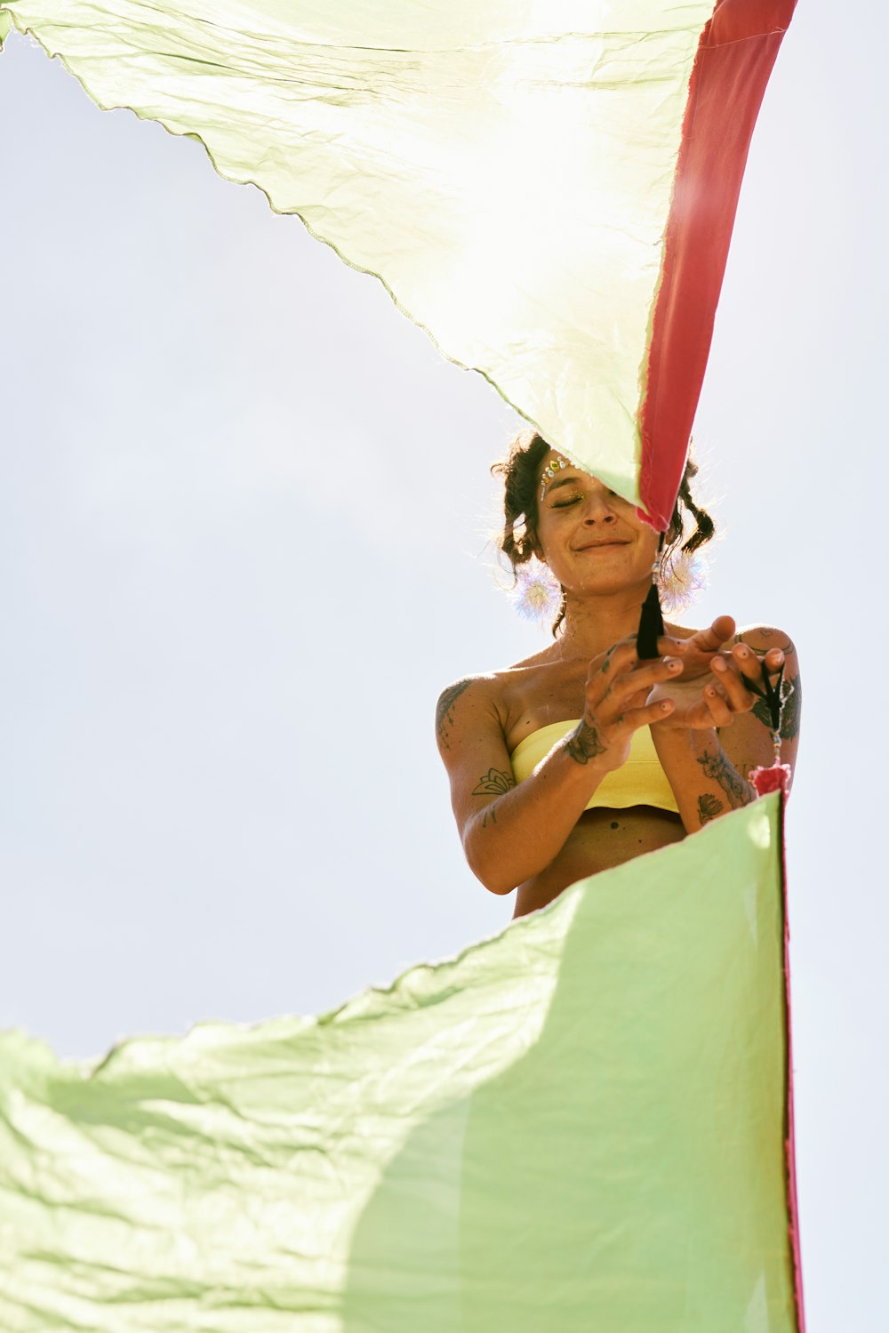 Une femme en bikini jaune tenant un parapluie rouge et blanc