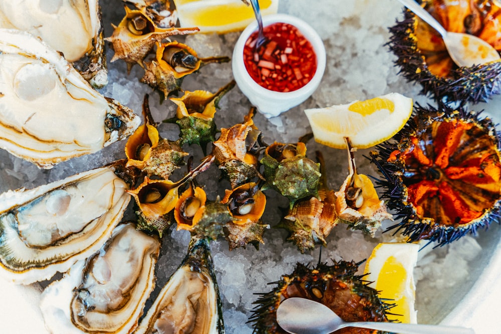 a platter of oysters on ice with lemon wedges