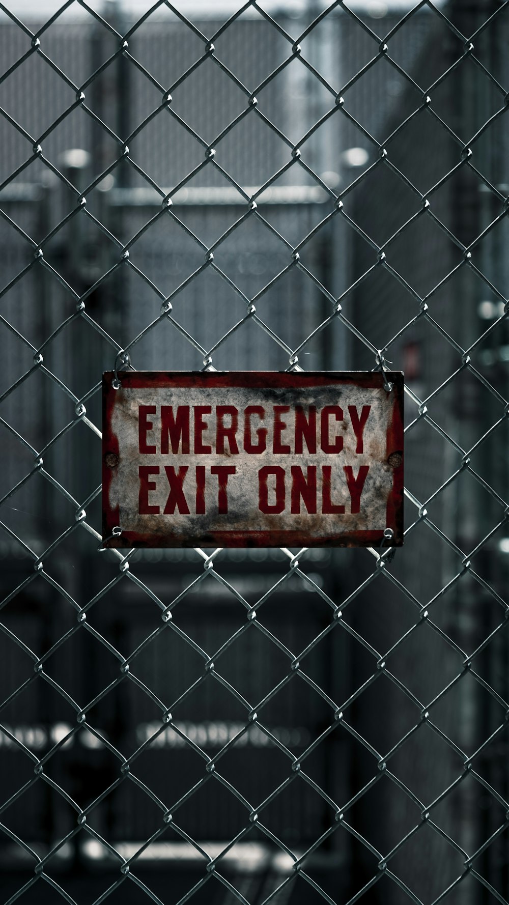 a red emergency exit only sign on a chain link fence