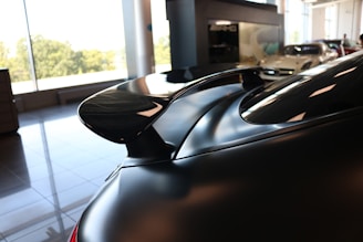 Side view of a sleek black car with a flawless wax finish in a garage