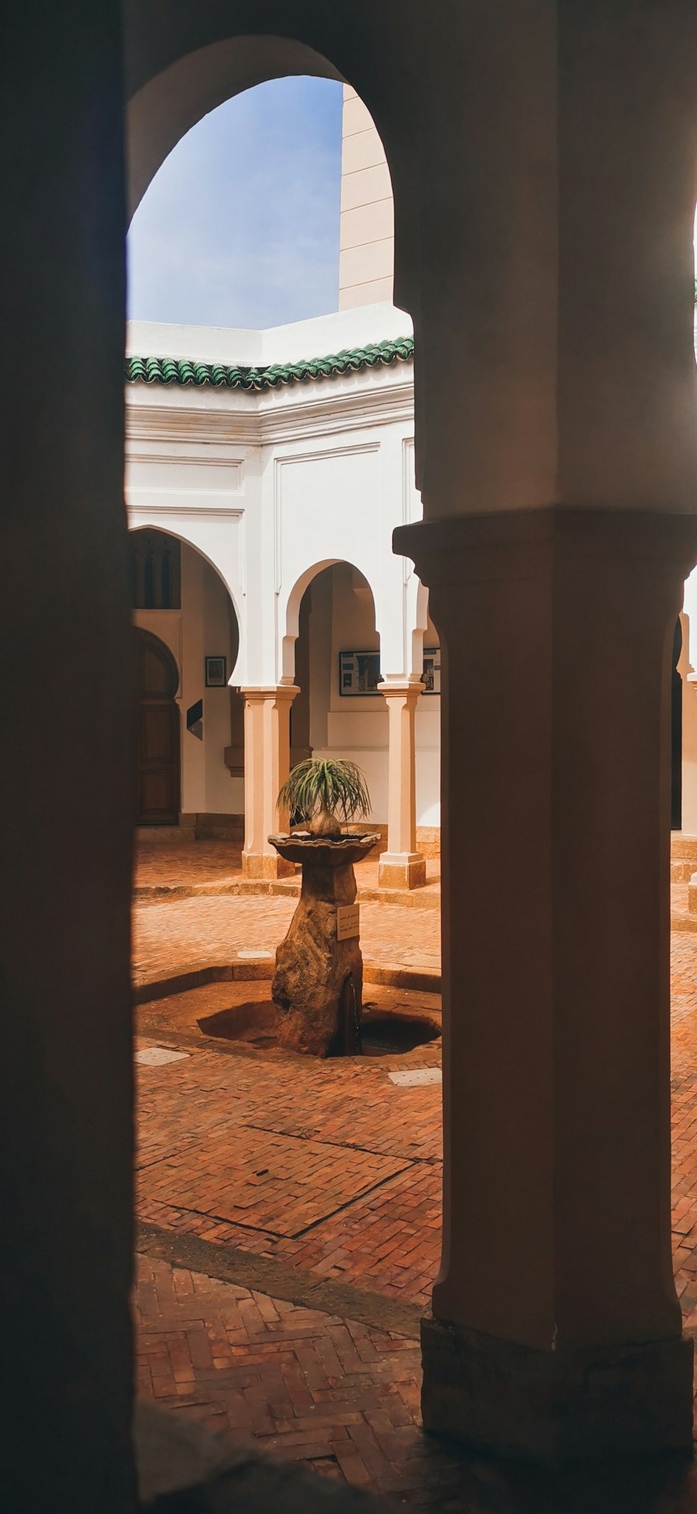 a courtyard with arches and a potted plant