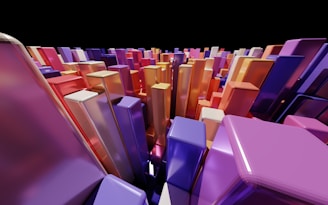 A collection of colorful, glossy, rectangular prisms arranged closely together, creating a sense of depth and perspective. The prisms display various shades of purple, orange, red, and blue, against a black backdrop, giving a vibrant and dynamic appearance.