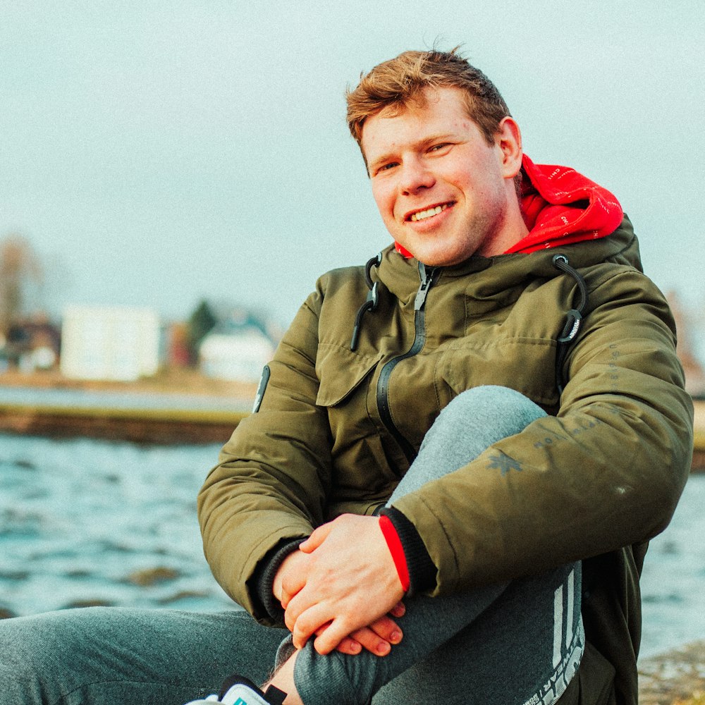 a man sitting on a rock next to a body of water