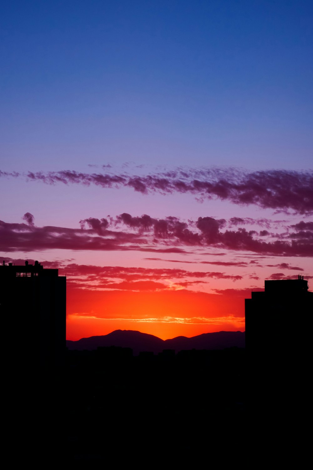 the sun is setting over a city with tall buildings