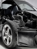 A detailed view of a car with its exterior partially removed, exposing the internal components. The image focuses on the wheel, suspension, and other mechanical parts, highlighting the intricate design and engineering.