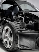 A detailed view of a car with its exterior partially removed, exposing the internal components. The image focuses on the wheel, suspension, and other mechanical parts, highlighting the intricate design and engineering.