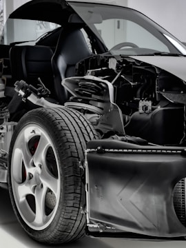 A detailed view of a car with its exterior partially removed, exposing the internal components. The image focuses on the wheel, suspension, and other mechanical parts, highlighting the intricate design and engineering.