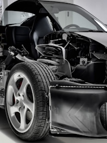 A detailed view of a car with its exterior partially removed, exposing the internal components. The image focuses on the wheel, suspension, and other mechanical parts, highlighting the intricate design and engineering.