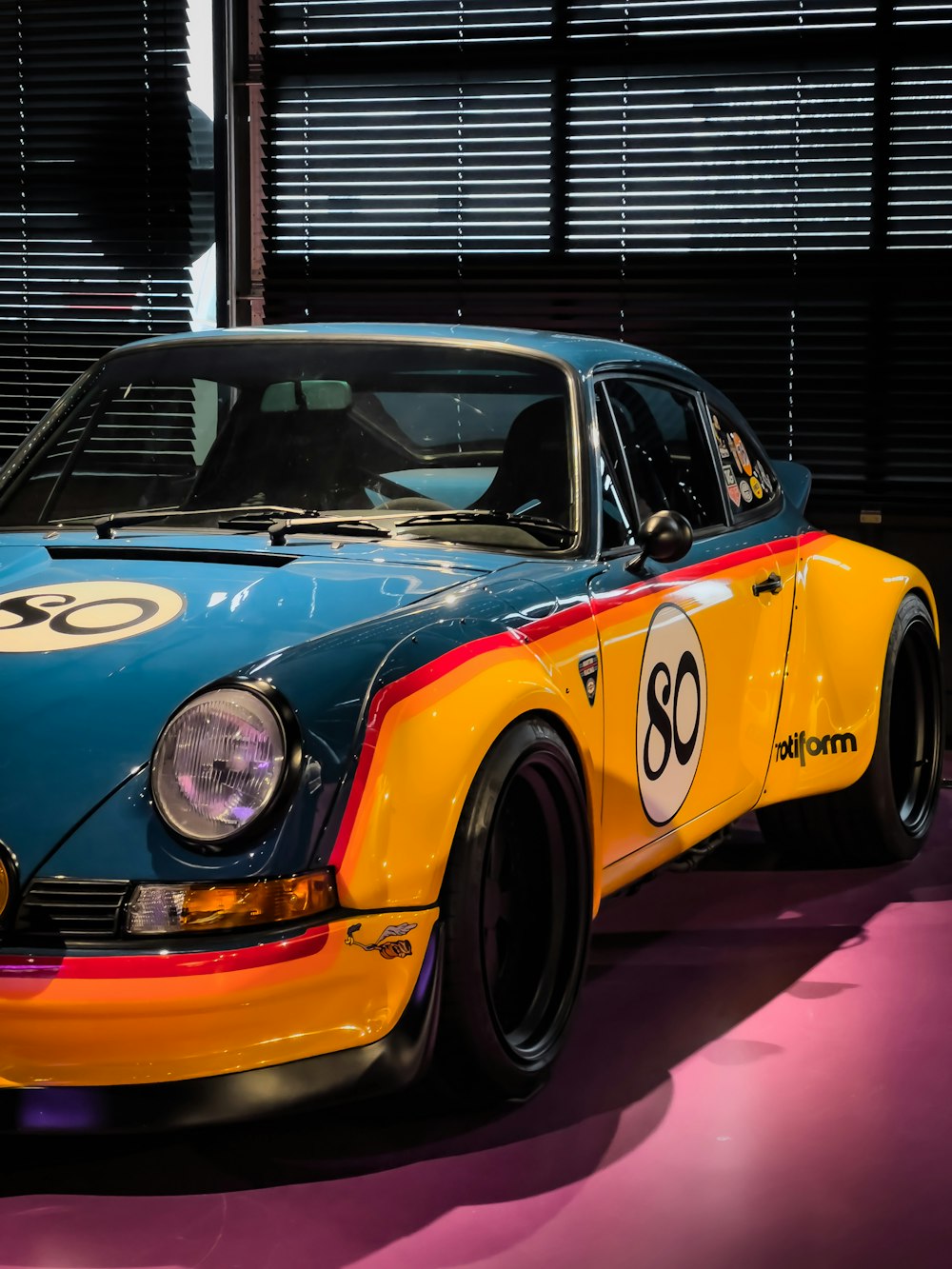 a yellow and blue sports car parked in a garage