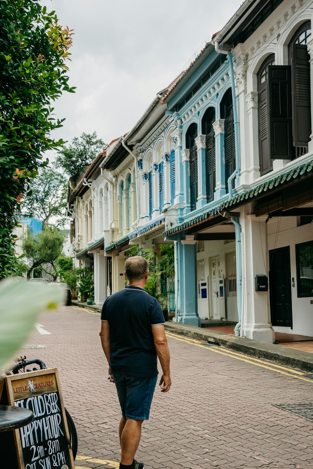 a man walking down a street next to tall buildings