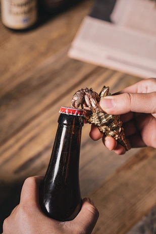 Hands using the odpirač can opener effortlessly on a large can in a bustling pizzeria kitchen.