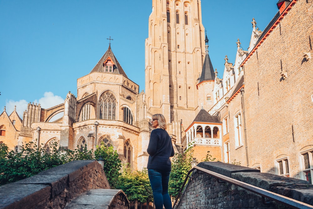 a woman standing on a bridge in front of a church