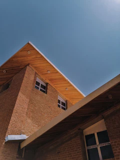 Modern house frame with steel beams and brick walls under clear blue sky.