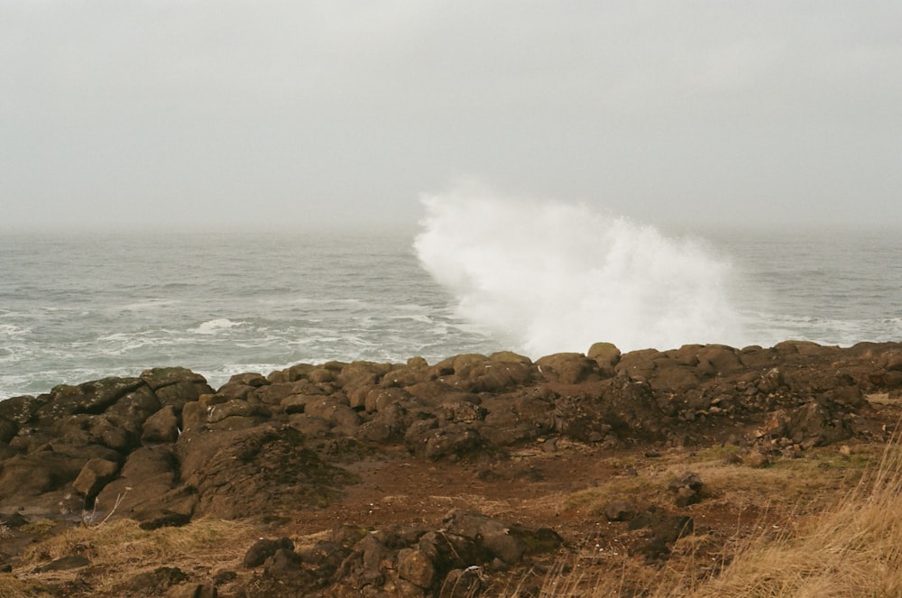 a large wave crashing over a rocky shore