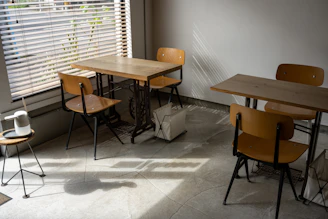 A sunlit corner of Café Claremont with wooden tables, potted plants, and a steaming cup of coffee on a white plate.
