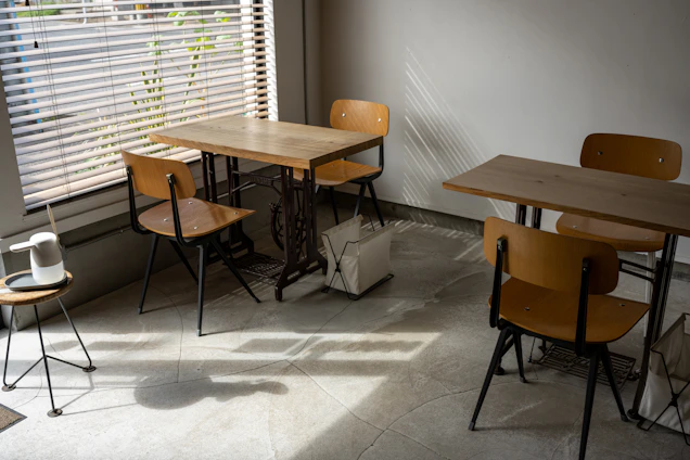 A sunlit corner of Café Claremont with wooden tables, potted plants, and a steaming cup of coffee on a white plate.