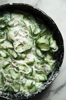 a bowl of cucumbers and onions on a table