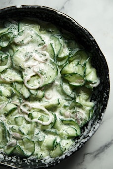a bowl of cucumbers and onions on a table